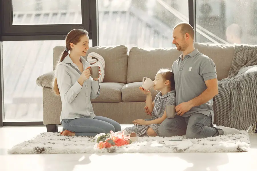 Glueckliche Familie geniesst gemeinsam ihr neues Zuhause im hellen Wohnzimmer